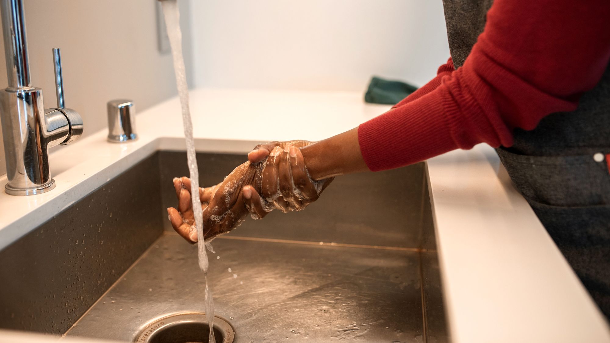 Lavage des mains au savon sous le robinet d’un évier inox, avant de reprendre son poste en cuisine