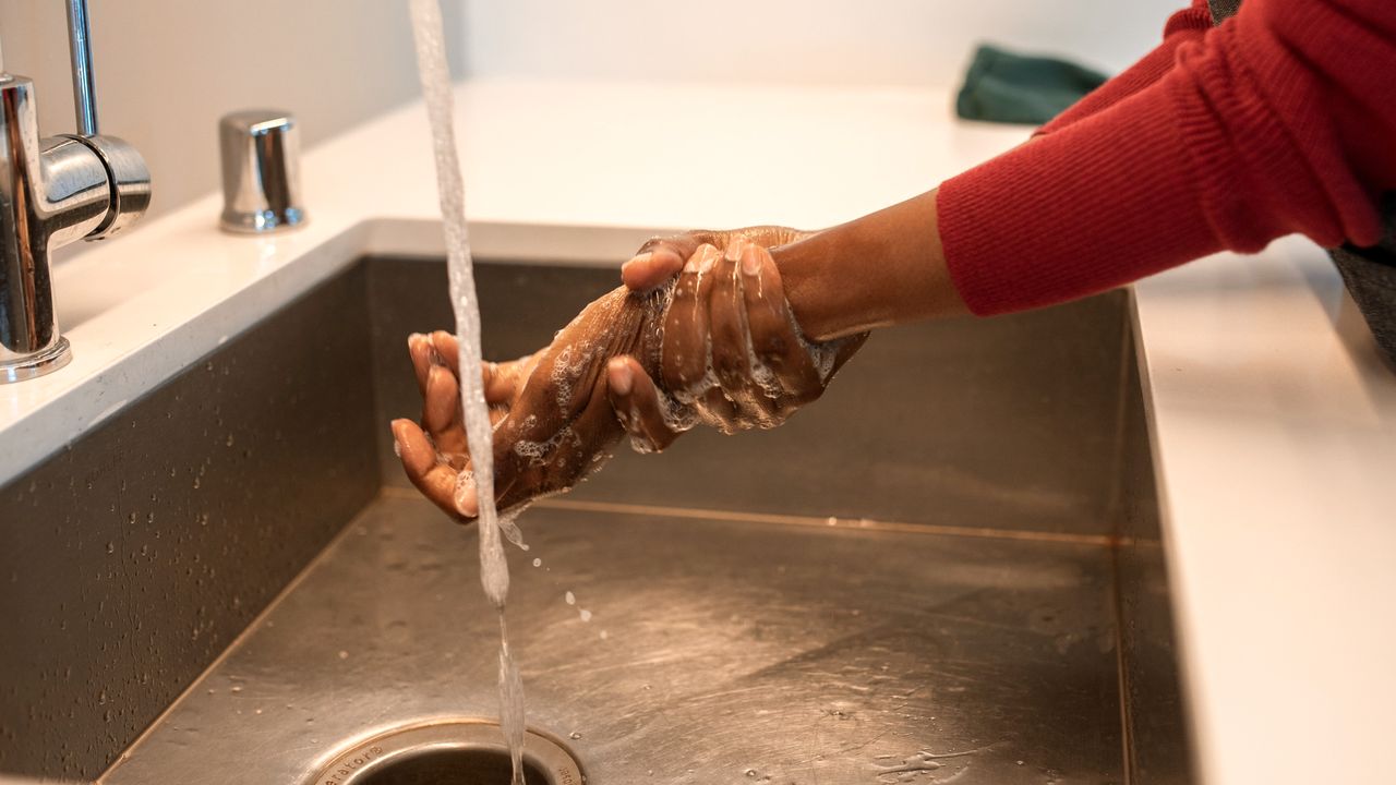 Lavage des mains au savon sous le robinet d’un évier inox, avant de reprendre son poste en cuisine